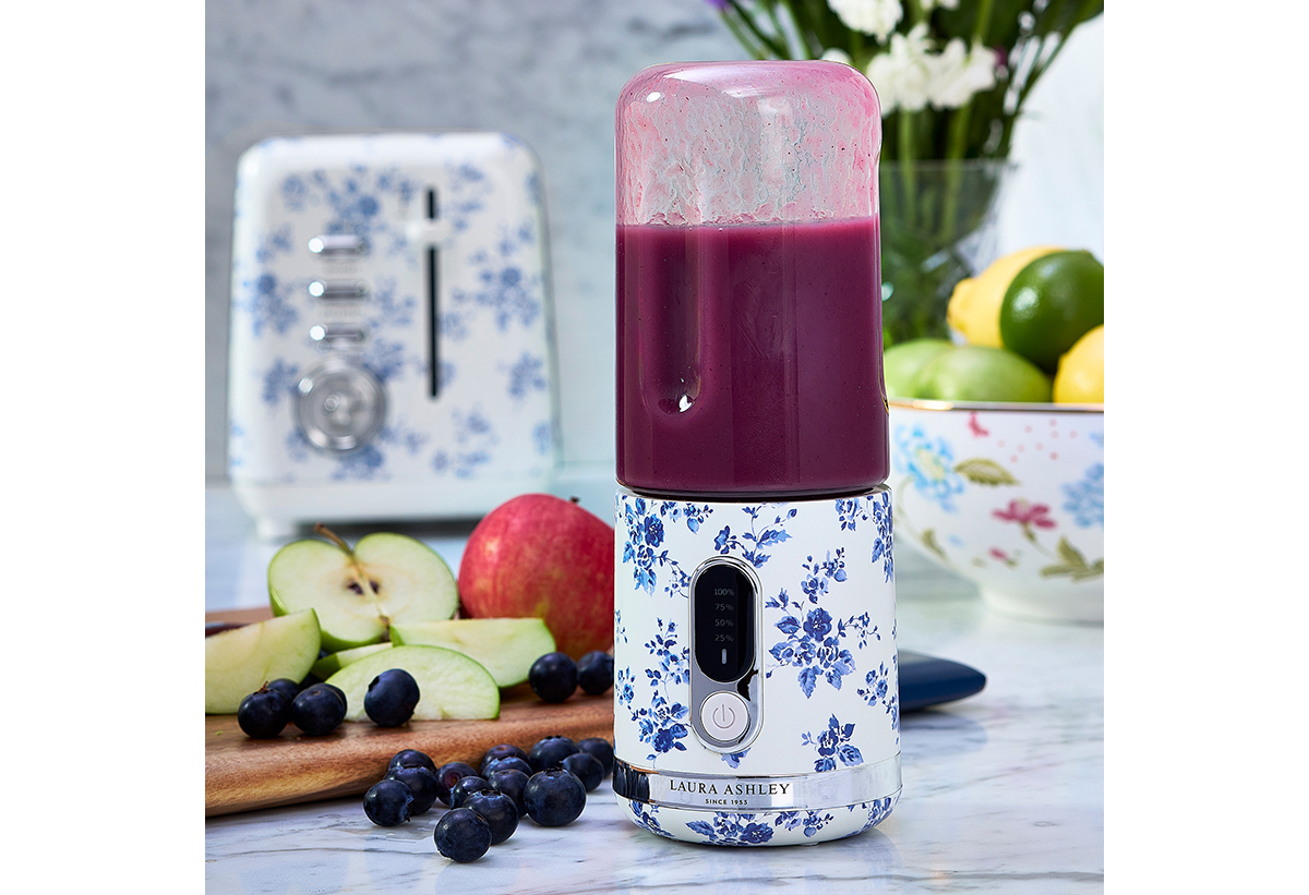 Απεικονίζεται το μπλέντερ με χυμό μέσα και φρούτα γύρω του.